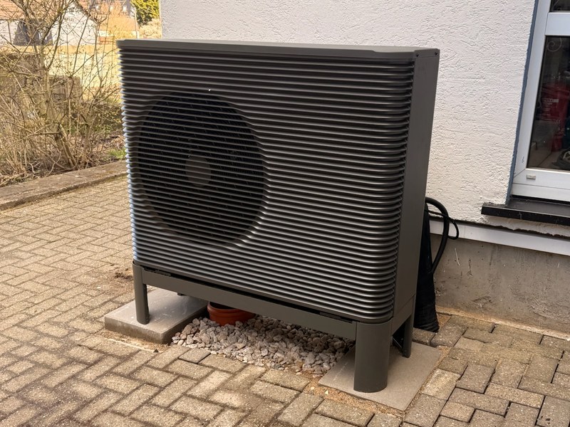 Aira Wärmepumpe: Außengerät an der Hauswand von Familie elektrisiert