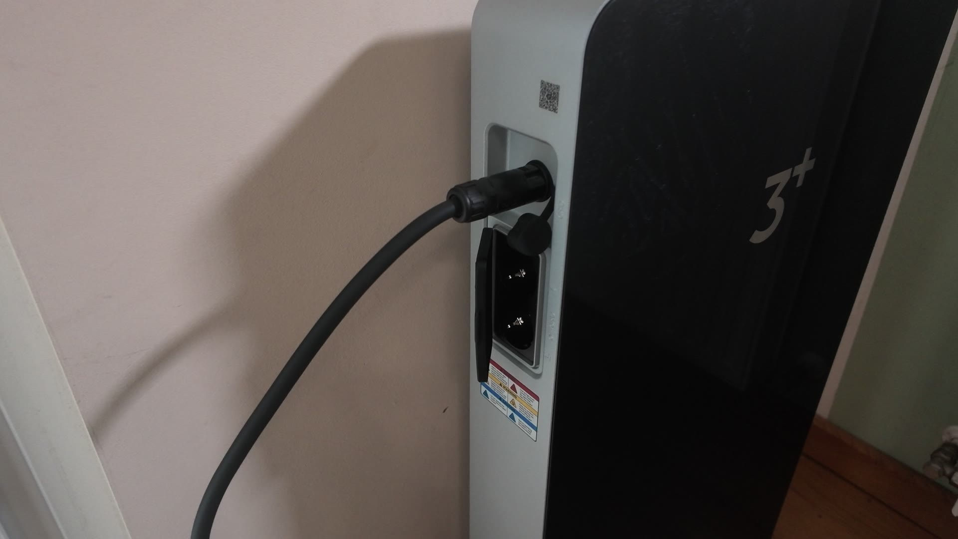 Seitliche Notstromsteckdosen des SAMDUO Nex E6000 mit geöffneter Schutzklappe, daneben ein angeschlossenes Kabel am Netzanschluss und ein Warnaufkleber.
