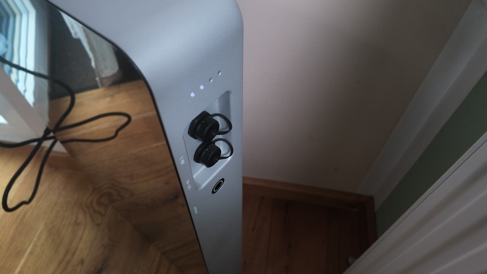 Seitliche Anschlussleiste des SAMDUO Nex E6000 mit zwei verschlossenen Steckanschlüssen, einem Taster und vier Status-LEDs, an der Silberkante neben der Glasfront.