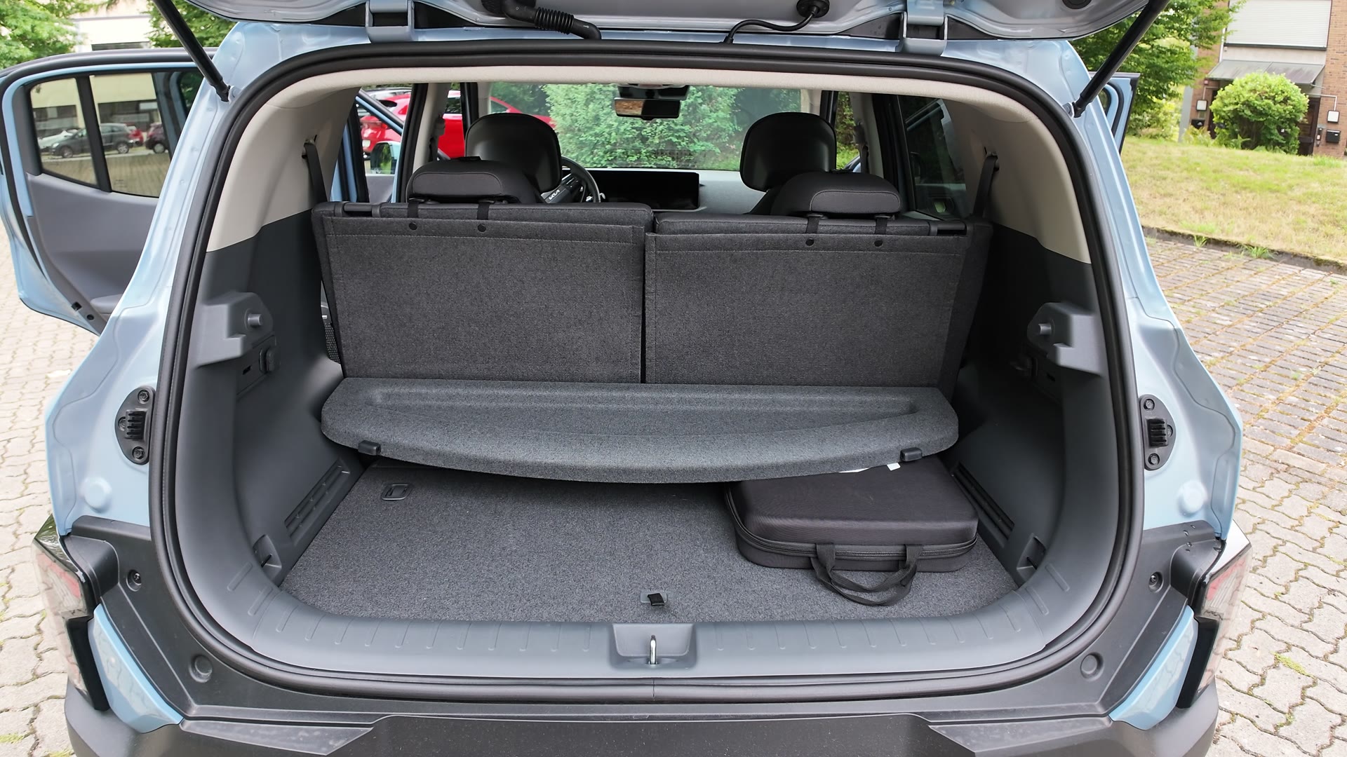 Offener Kofferraum des Kia EV2 mit Laderaumabdeckung, aufrechten Rücksitzlehnen und einer schwarzen Tasche auf dem Ladeboden.